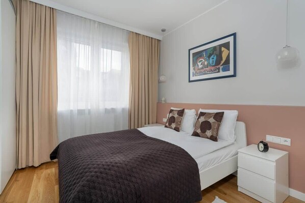 A cozy bedroom with a large bed, a framed artwork, and soft lighting.

