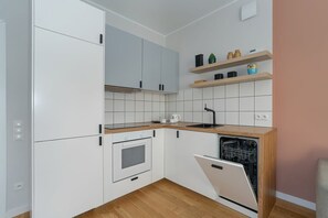 A stylish kitchen with white cabinets, wooden countertops, and tiled walls.


