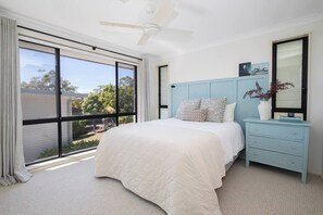 Indulge in the coastal charm of the first bedroom, featuring a comfortable queen-sized bed, a convenient bedside chest, and tasteful accents in a soothing seafoam blue hue for a serene beachy ambience.