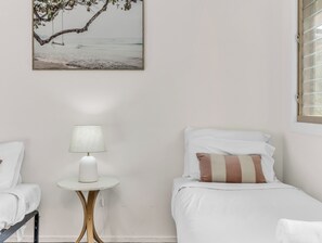Thoughtfully designed twin bedroom with clean lines, neutral tones, and a serene coastal print for a calm, airy feel.