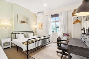 The bright and spacious first bedroom features a king-size bed and air conditioning, while a designated workspace allows for uninterrupted remote work.