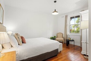 The spacious primary bedroom highlights a queen-size bed, a cosy reading nook, and ample storage space for your things