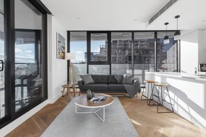 The sun-lit lounge area seamlessly connects to the kitchen and provides modern seating as well as a TV
