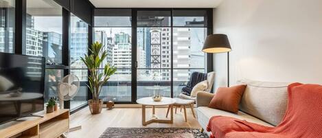 The living room showcases floor-to-ceiling windows revealing impressive city views.

