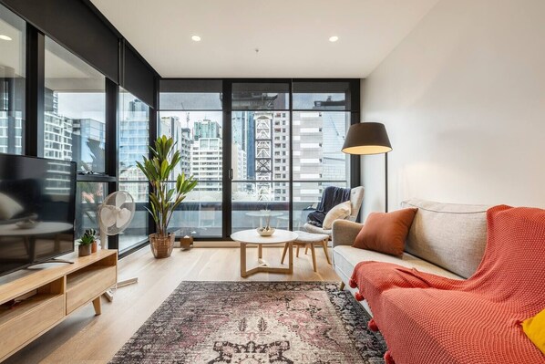 The living room showcases floor-to-ceiling windows revealing impressive city views.
