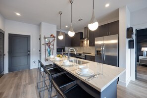 Fully equipped kitchen stocked with your basic cooking essentials. Includes stainless steel appliances, small kitchen island, coffee machine, and toaster.