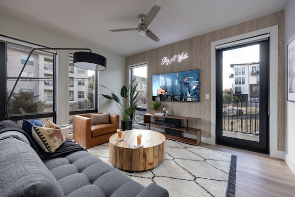 Bright open living space featuring a smart flat-screen TV, designer furnishings, and access to the private patio.