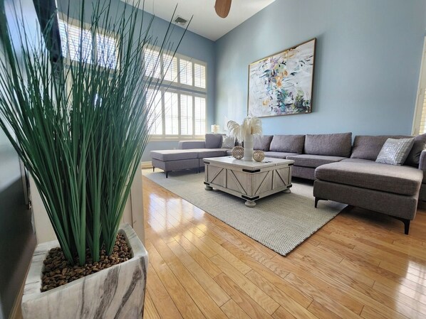 Spacious, bright and comfortable living room with section couch, ceiling fan and TV. 