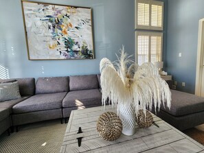 Spacious, bright and comfortable living room with section couch, ceiling fan and TV. 