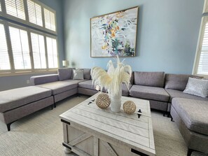 Spacious, bright and comfortable living room with section couch, ceiling fan and TV. 