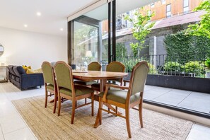 An open-plan dining area features a six-seater table, with tranquil views looking out to the shared courtyard and garden.
