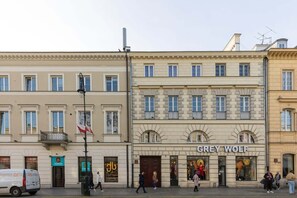 The building’s historic facade with tall windows and decorative details above street-level shops.