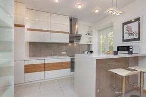 A modern kitchen featuring white and wooden cabinets, a breakfast bar, and built-in appliances.
