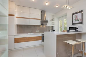 A modern kitchen featuring white and wooden cabinets, a breakfast bar, and built-in appliances.