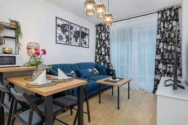 A stylish dining area with a dark wooden table, blue velvet chairs, and decorative artwork.
