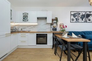 A bright kitchen with white cabinets, wooden countertops, and a dining area.
