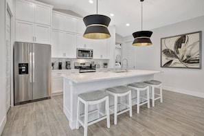 The open kitchen has stainless steel appliances and a large counter with seating for 4