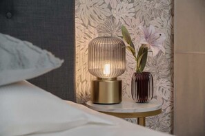 A stylish nightstand with a gold lamp and textured wallpaper in the bedroom.
