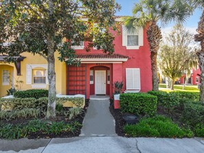 Charming townhouse entrance with colorful exterior and landscaped walkway.