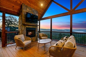 The outdoor living area with a sofa and chairs around a gas fireplace.