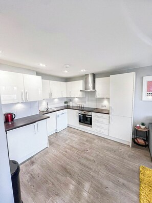 Modern kitchen with sleek white cabinets, ample counter space, and fully equipped with all the essentials for a convenient stay.