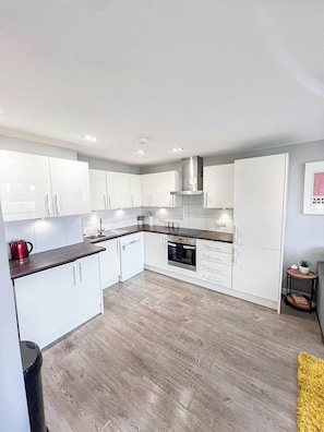 Modern kitchen with sleek white cabinets, ample counter space, and fully equipped with all the essentials for a convenient stay.