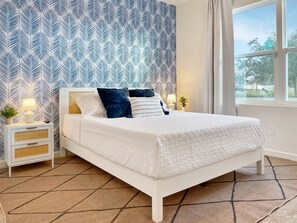 [Bedroom 2] Relax in our Palm Beach bedroom. A Smart TV is mounted across from the queen bed