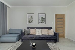 Another angle of the living area showing the blue sectional sofa, coffee table, and elegant decor accents.


