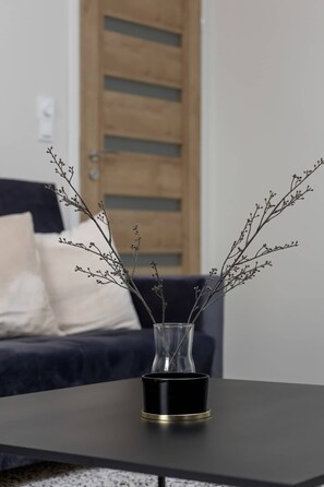 A close-up of a decorative vase with minimalist branches on a dark wooden table.

