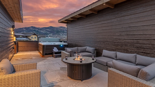 Rooftop patio with gas fireplace, comfortable seating, and hot tub