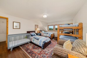 Bunk room with cozy couch, set of bunks, 2 twin beds, and crib.
