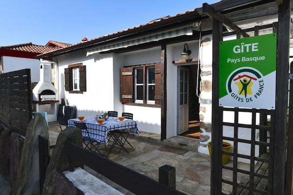 La terrasse et l'entrée du gîte: salon de jardin + plancha