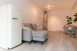 Stylish lounge area with retro fridge, plush seating and soft lighting — feel right at home.

