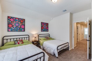 A bright and minimalistic bedroom featuring a white metal-frame bed, soft linens, and elegant black-and-white artwork for a peaceful, inviting retreat.