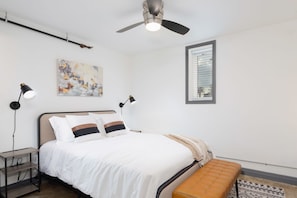 
This bedroom is a sanctuary of simplicity, radiating minimalist Scandinavian charm. A pristine white comforter drapes the bed, inviting you to relax beneath a captivating wall painting. A chic lamp on the nightstand enhances the serene ambiance, perfectly complemented by light-toned wood flooring and crisp white walls. Experience modern elegance in this uncluttered haven.