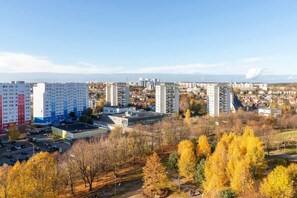 An elevated cityscape view showcasing tall residential blocks surrounded by autumn-colored trees under a clear sky.

