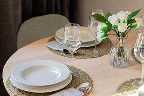 A close-up of a dining table set with elegant gold placemats, white dinnerware, and a small floral centerpiece.

