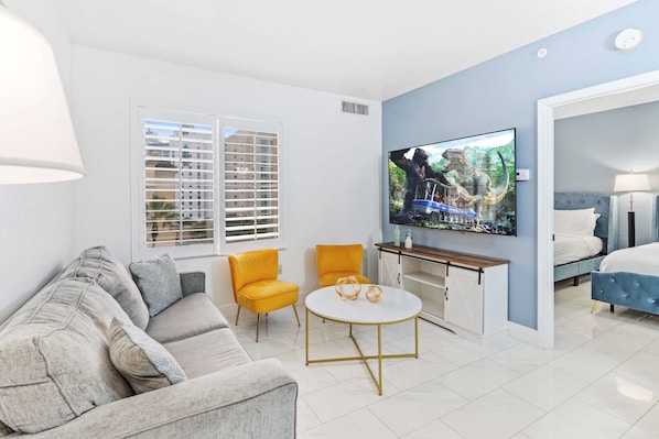 Living room with large smart TV, sleeper sofa and kitchen