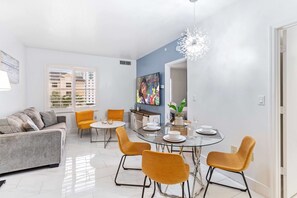 Living room with large smart TV, sleeper sofa and kitchen
