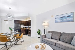 Living room with large smart TV, sleeper sofa and kitchen