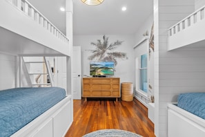 Stylish bunk room with ocean-inspired decor, cozy blue bedding, and a TV.