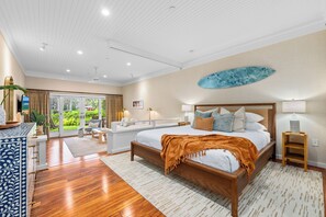 Spacious bedroom with elegant décor, wood accents, and lush garden views.