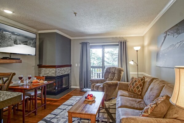 View of living room with electric fire place, dining area and door way to balcony