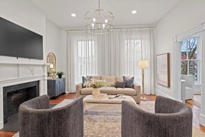 A cozy living room featuring a stylish setup with a large flat-screen TV mounted above a modern fireplace.