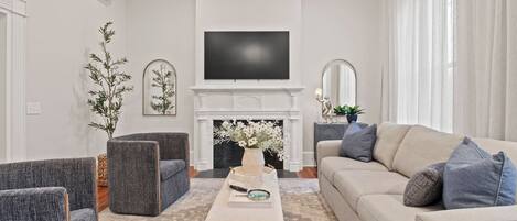 A cozy living room featuring a stylish setup with a large flat-screen TV mounted above a modern fireplace.