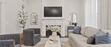 A cozy living room featuring a stylish setup with a large flat-screen TV mounted above a modern fireplace.
