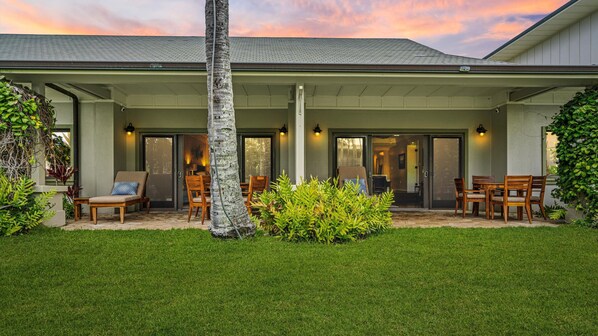 Outdoor patio with furniture, enjoying the green lawn while hearing the waves.