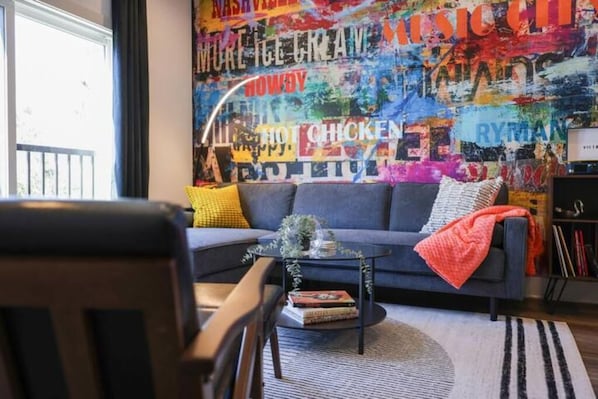 Cozy living room with custom mural and plenty of seating and natural light.