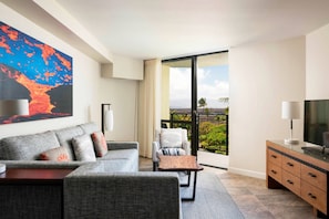 Living room features a sleeper sofa, TV, and door to a private balcony.