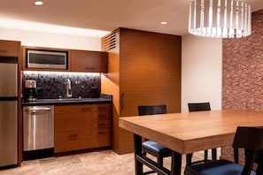 Kitchenette includes refrigerator, dishwasher, microwave, coffeemaker, dishes, glasses, and utensils. Dining area features a table for four guests.